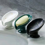 Three decorative soap holders on a marble surface with a bar of soap.