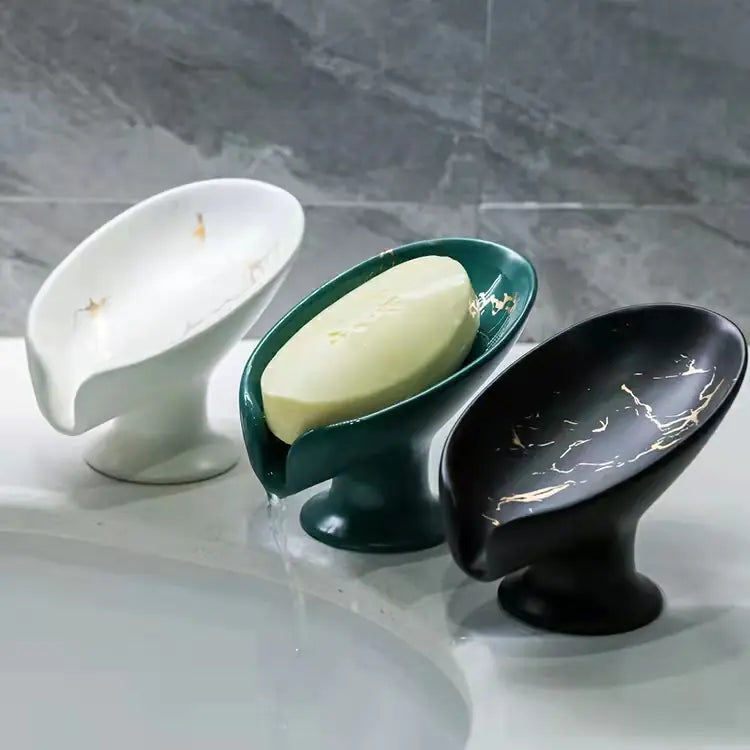 Three decorative soap holders on a marble surface with a bar of soap.