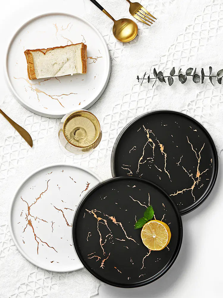 Set of black marble-patterned plates with a lemon wedge on a white surface.