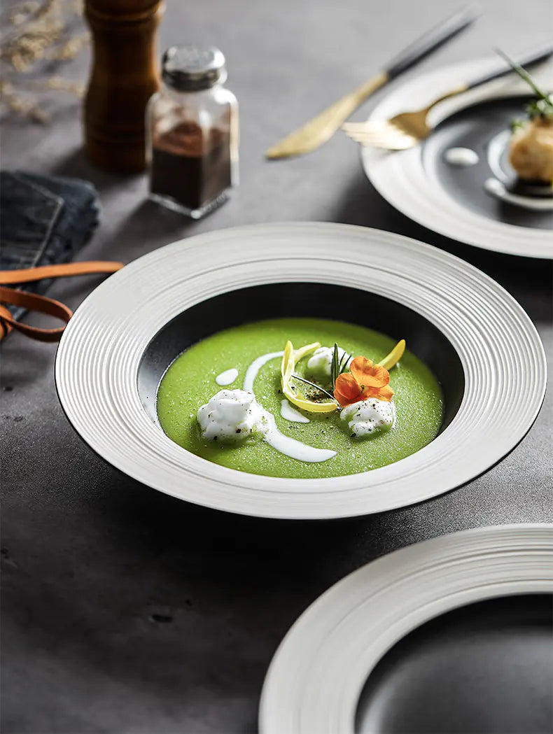 Green soup in a white bowl with garnishes on a dark surface