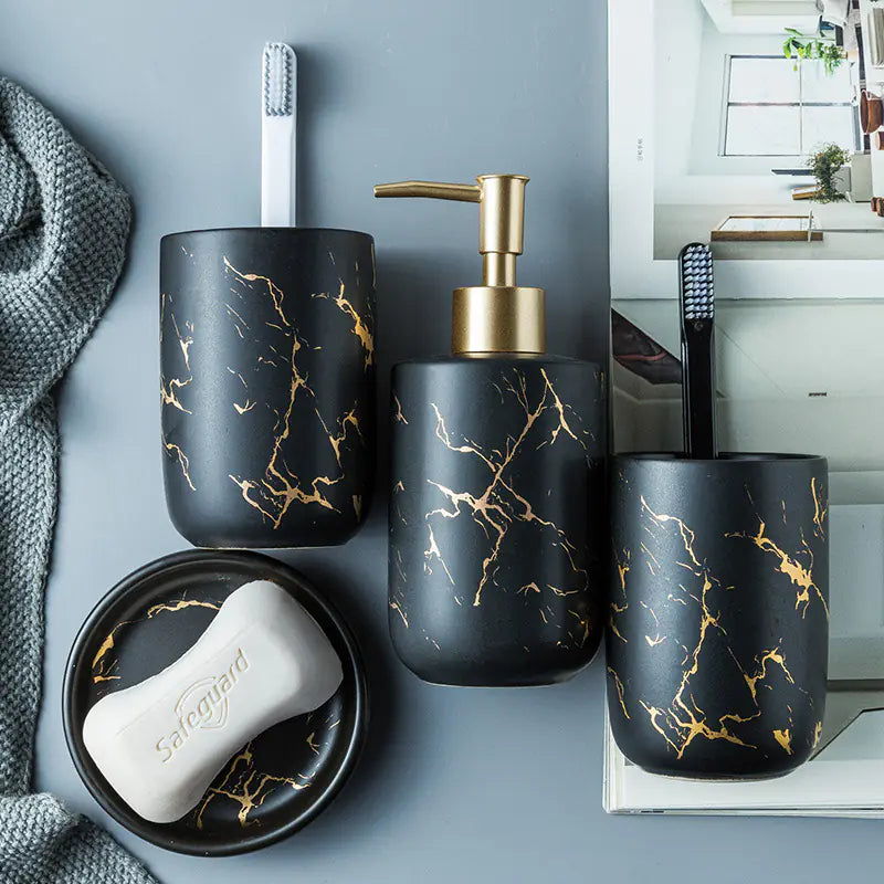 Bathroom set with black and gold marbled design including a soap dispenser, toothbrush holder, and soap dish.