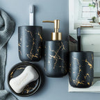 Bathroom set with black and gold marbled design including a soap dispenser, toothbrush holder, and soap dish.