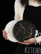 Person holding two decorative trays with marble-like patterns against a black background